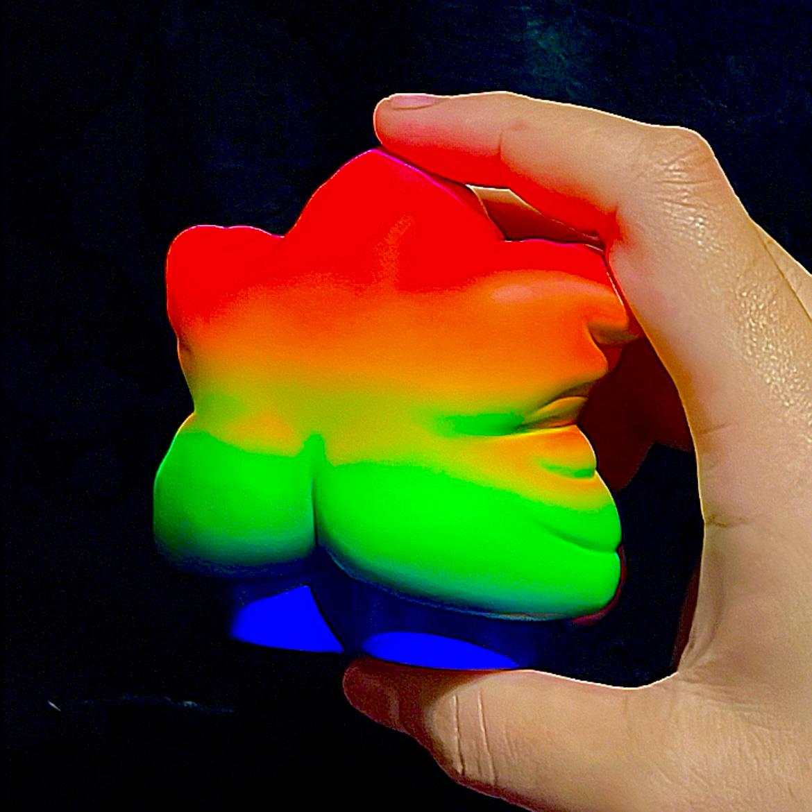 A hand holding a colorful object, part of Rainbow Weee baby - Preorder.