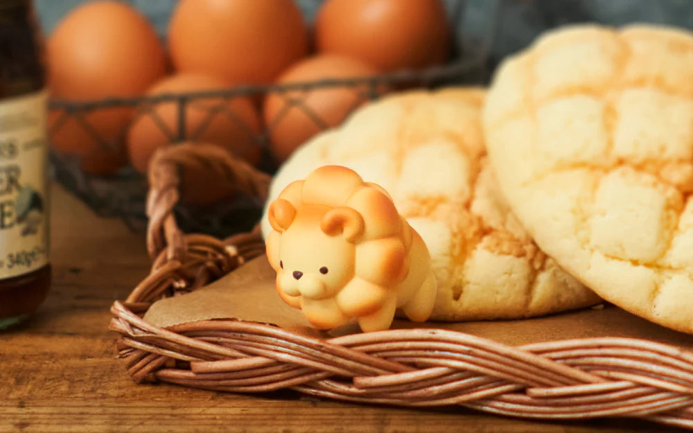 Animal Bakery Minifigure: Series 2 features a bread lion, intricately designed, resembling a baked animal, showcased on a basket. Blind box surprise from Strangecat Toys.