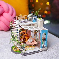 Rolife Dora's Loft DIY Miniature House kit featuring stairs, bed, couch, and plant. A whimsical toy for indoor fun, embodying the spirit of Strangecat Toys. Dimensions: 8.3 x 2.6 x 10.5 in.