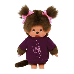 A Mini Monchhichi doll with a red bib, thumb in mouth, and Tee Love Dress Girl outfit. Soft body, plastic head, hands, and feet for cuddling and adventures. Ideal for collectors and fans.