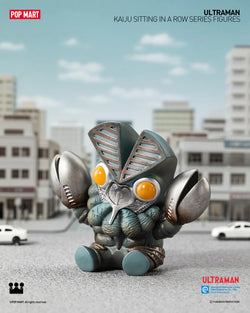 Ultraman KAIJU toy figure in cityscape with large eyes, white car, logo, yellow button, and metal object.