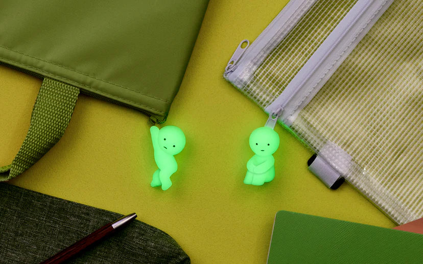 Smiski ZipperBites keychain featuring two small glowing dolls beside a zippered bag, perfect for finding keys in the dark.