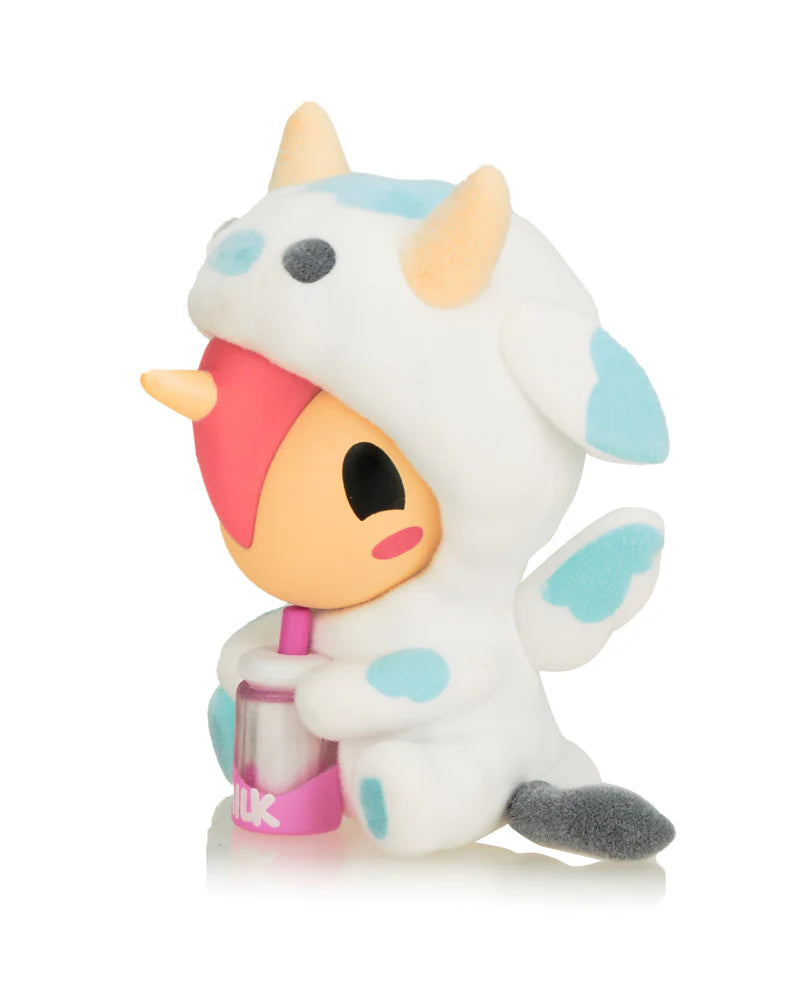 Cozy Unicorno Blind Box featuring a stuffed animal in a unicorn garment, holding a milk bottle, showcasing collectible art from Strangecat Toys.