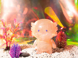 A plastic toy monster in an aquarium with a shiny face and plant details.