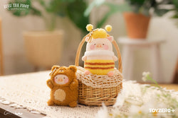 A plush pig and teddy bear in a basket, with a keychain toy and a puffy ball.