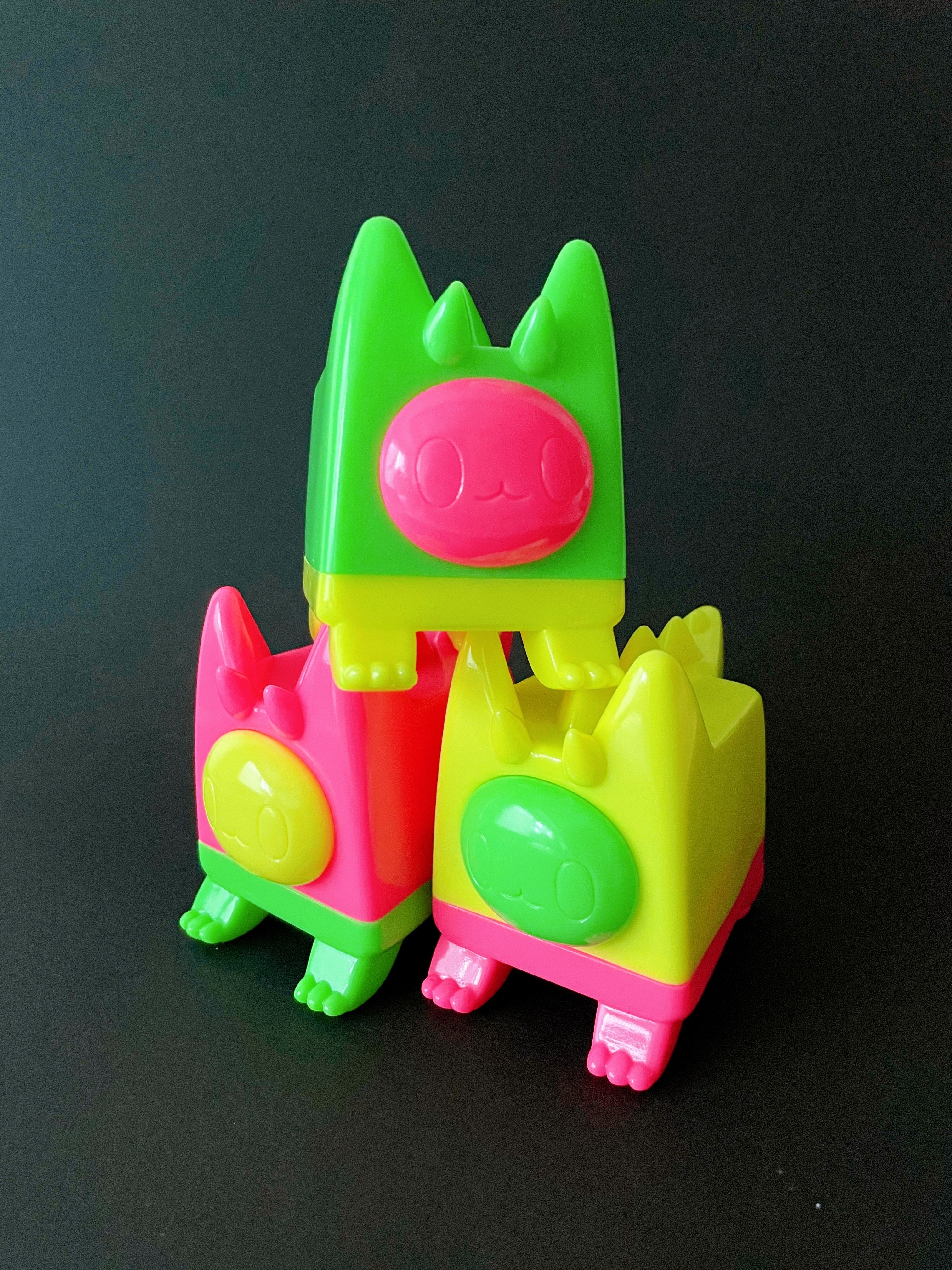 Dinocat - DIDI by Rato Kim, a group of plastic toys including a stack and a green and yellow object with a pink face.