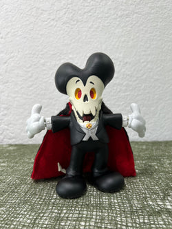 Toy figurine of Count Tibiula, a skeleton in a garment, mask, and vampire attire, with cartoon character and skull details.