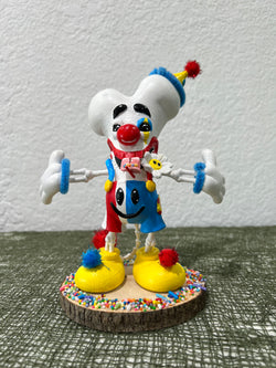 Toy clown with hat and legs, yellow pot with pom poms, red ball with face, blue and yellow ball.