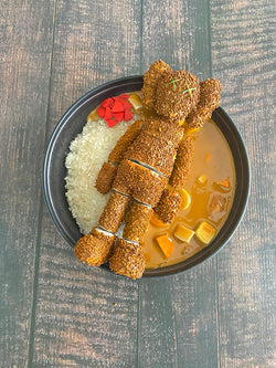 A stuffed bear in a bowl of rice, part of the Misappropriated Icon 6 Eat Up - Katsu Curry by Zard Apuya collection.