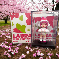 Toy figurine of a girl in a case next to a box, 14cm PVC+ABS Laura 150% The Snow Of Cherry Blossom Sakura.