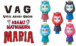 VAG 25 - Maria: A group of toy figurines, including a cartoon character with orange eyes and a girl figurine, in soft vinyl capsules.