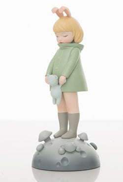 A toy figurine of a girl with a teddy bear, standing on a mushroom, holding a cat, and a doll in close-up view.