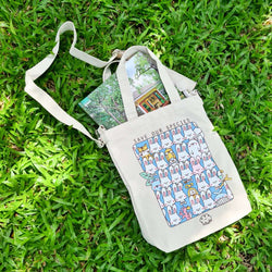 Save Our Species Tote by Kotton Factory featuring a bag with a book and rabbit illustrations on grass.